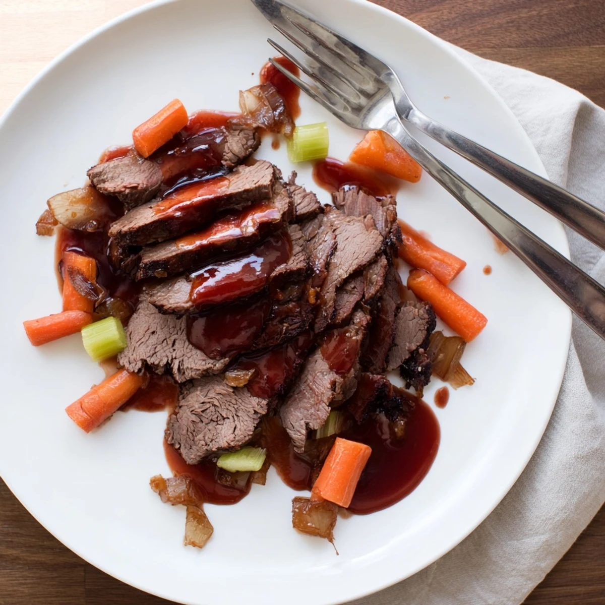 Fork-tender slow cooker beef brisket arranged on a white platter with roasted carrots and onions
