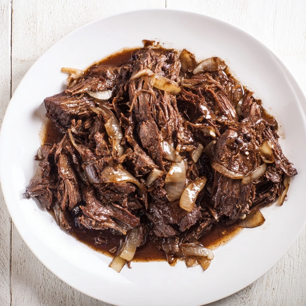 Flavorful slow-cooked shredded beef recipe nestled in a white ceramic bowl