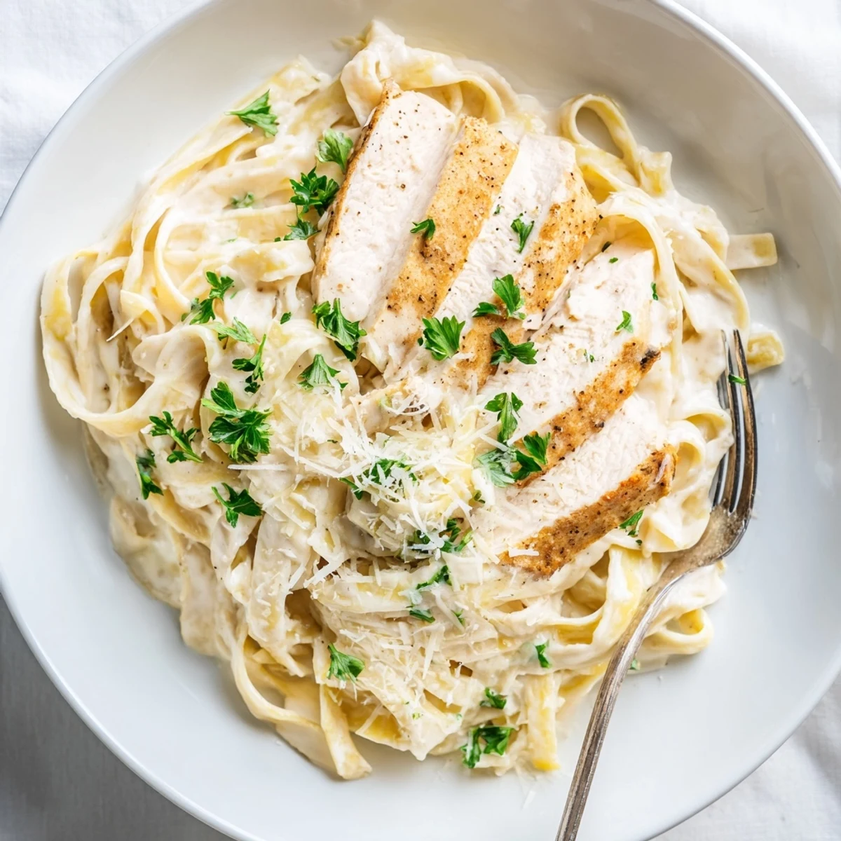 Creamy chicken alfredo pasta with tender sliced chicken breast over rich parmesan fettuccine