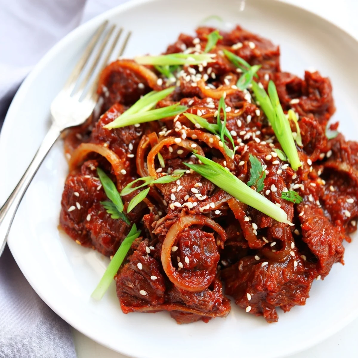 Slow cooker Korean beef braised to perfection with caramelized onions and garnished with fresh green onions