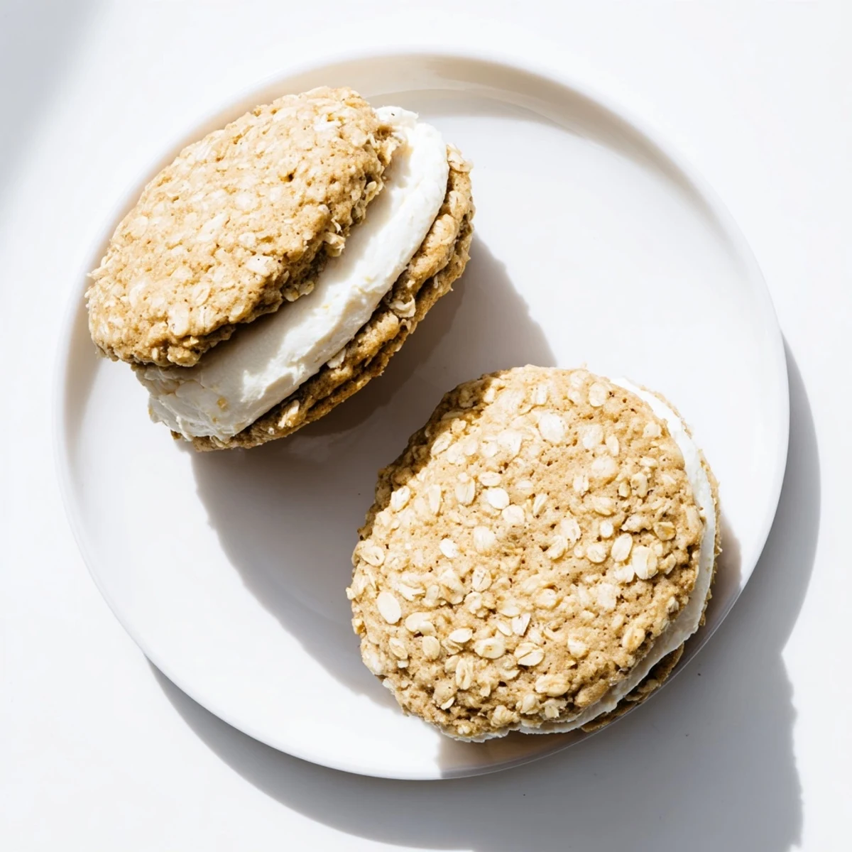 Two soft homemade oatmeal cream pies stacked with vanilla frosting dripping from the sides