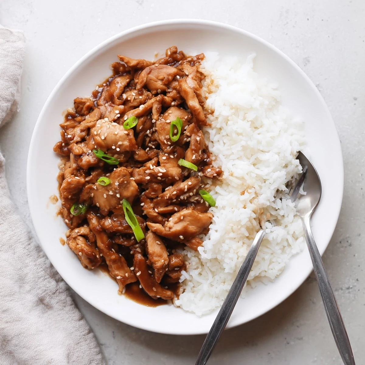 Slow cooker Mongolian chicken with tender shredded pieces coated in glossy brown sauce and garnished with green onions
