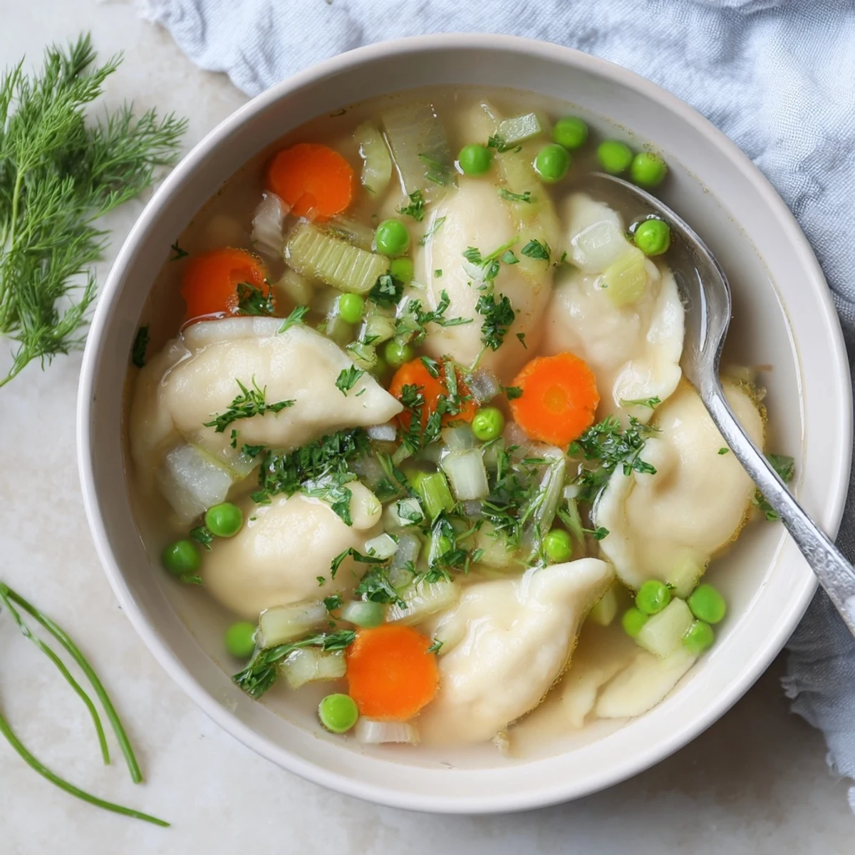 Steaming bowl of comforting dumpling soup featuring fluffy tender dumplings in savory vegetable broth with vibrant carrots and celery