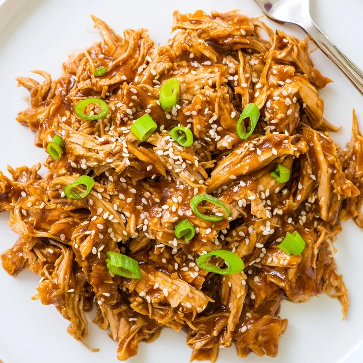 Golden brown Crockpot teriyaki chicken pieces coated in sticky sweet sauce garnished with green onions