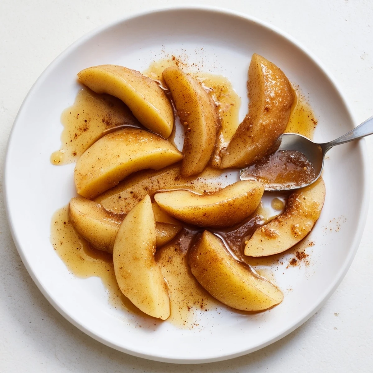 Golden brown Instant Pot cinnamon apples with warm spiced syrup served in white bowl