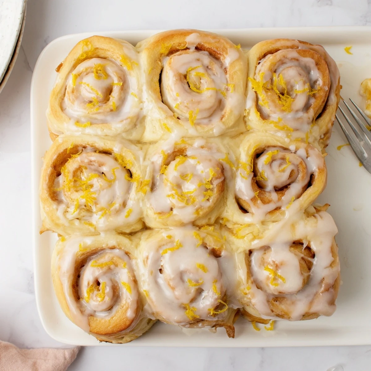 Warm homemade lemon rolls topped with creamy lemon glaze and garnished with zest