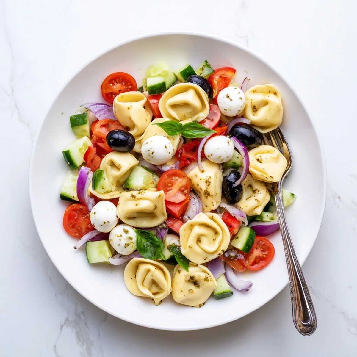 Cheese-filled tortellini pasta salad tossed with crisp vegetables, mozzarella, and fresh basil leaves