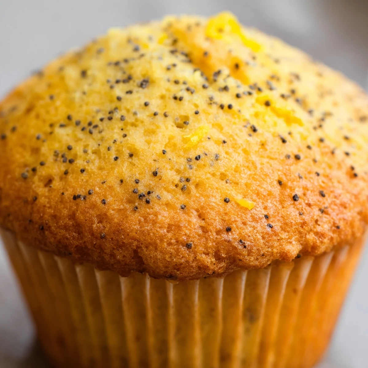 Moist lemon poppy seed muffins studded with speckled seeds served on a rustic ceramic plate