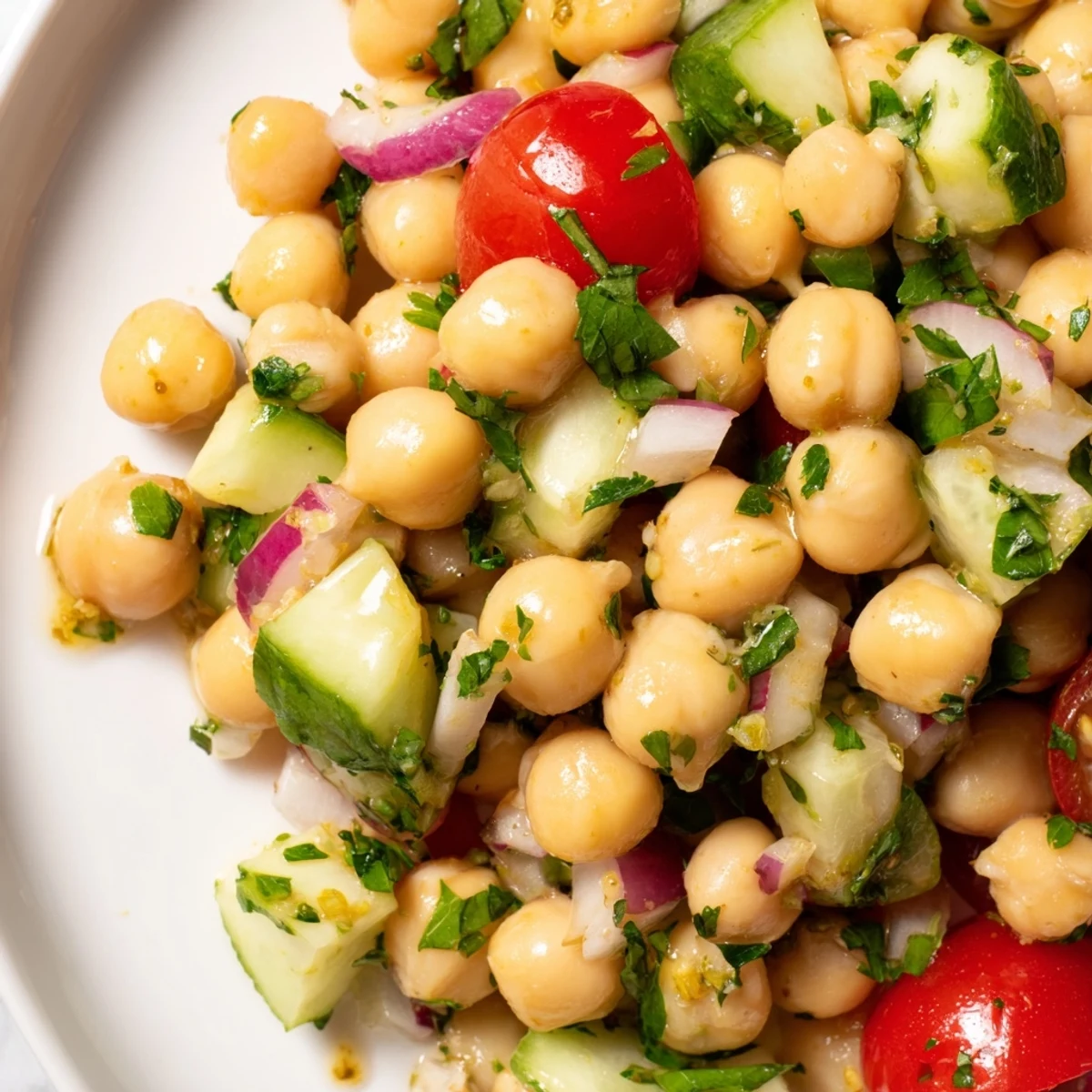 Colorful chickpea cucumber salad featuring ripe tomatoes, red onion, and bright parsley