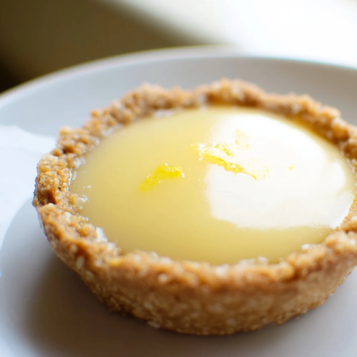 Golden mini vegan lemon tarts with silky custard filling topped with fresh berries