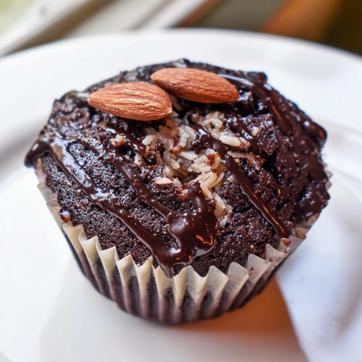 Decadent flourless almond joy cupcakes with gooey coconut centers drizzled in warm chocolate ganache