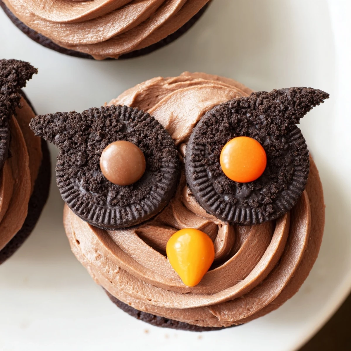 Oreo Owl Cupcakes with chocolate frosting and candy eyes on a rustic baking sheet