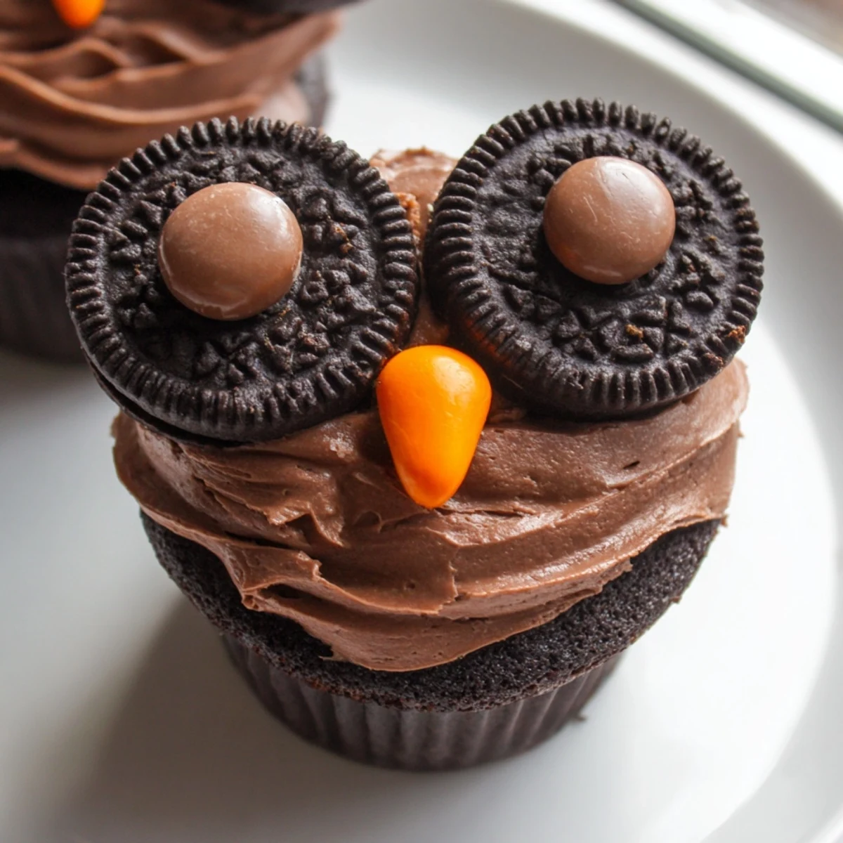 Cute Oreo Owl Cupcakes topped with creamy frosting and cookie eyes on a platter