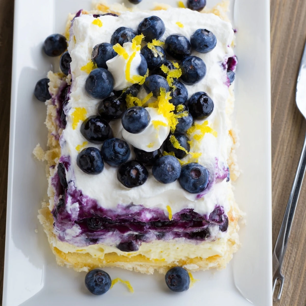 Chilled lemon blueberry lasagna in a glass dish topped with whipped cream