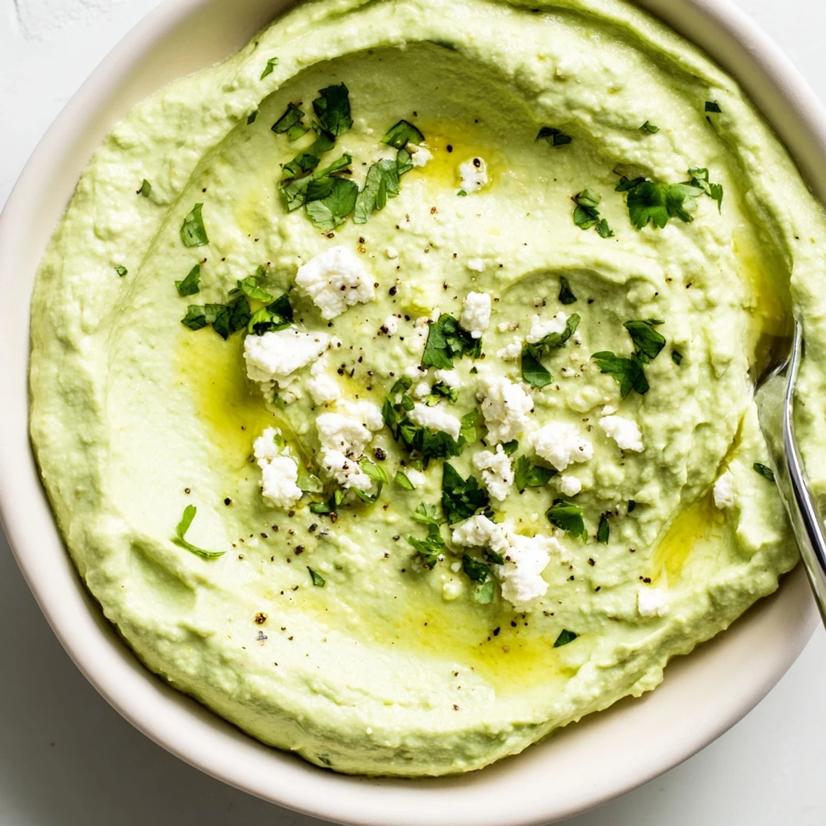 Creamy Avocado Feta Dip in a bowl with olive oil drizzle.