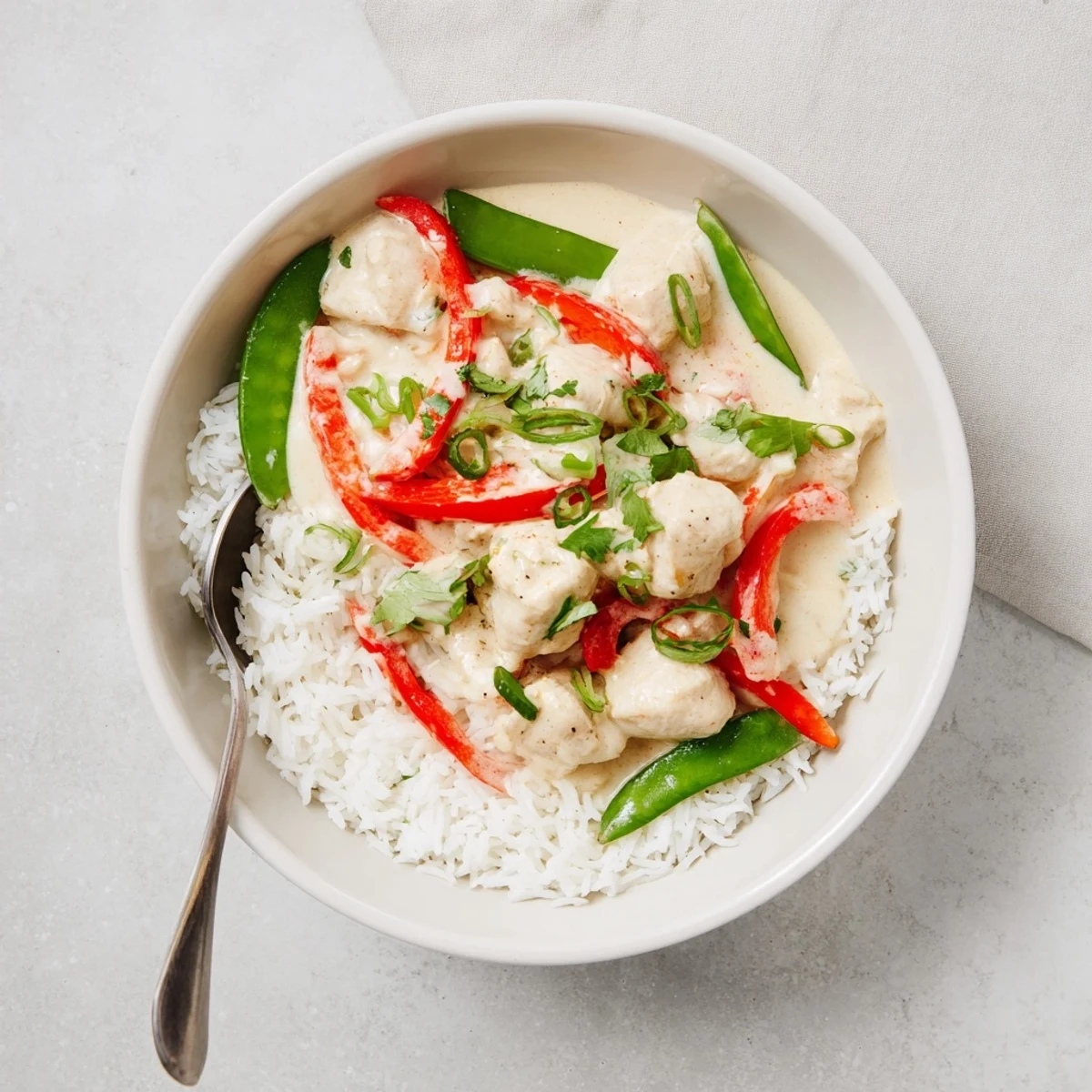 Creamy coconut chicken rice bowl topped with tender chicken pieces in rich coconut sauce
