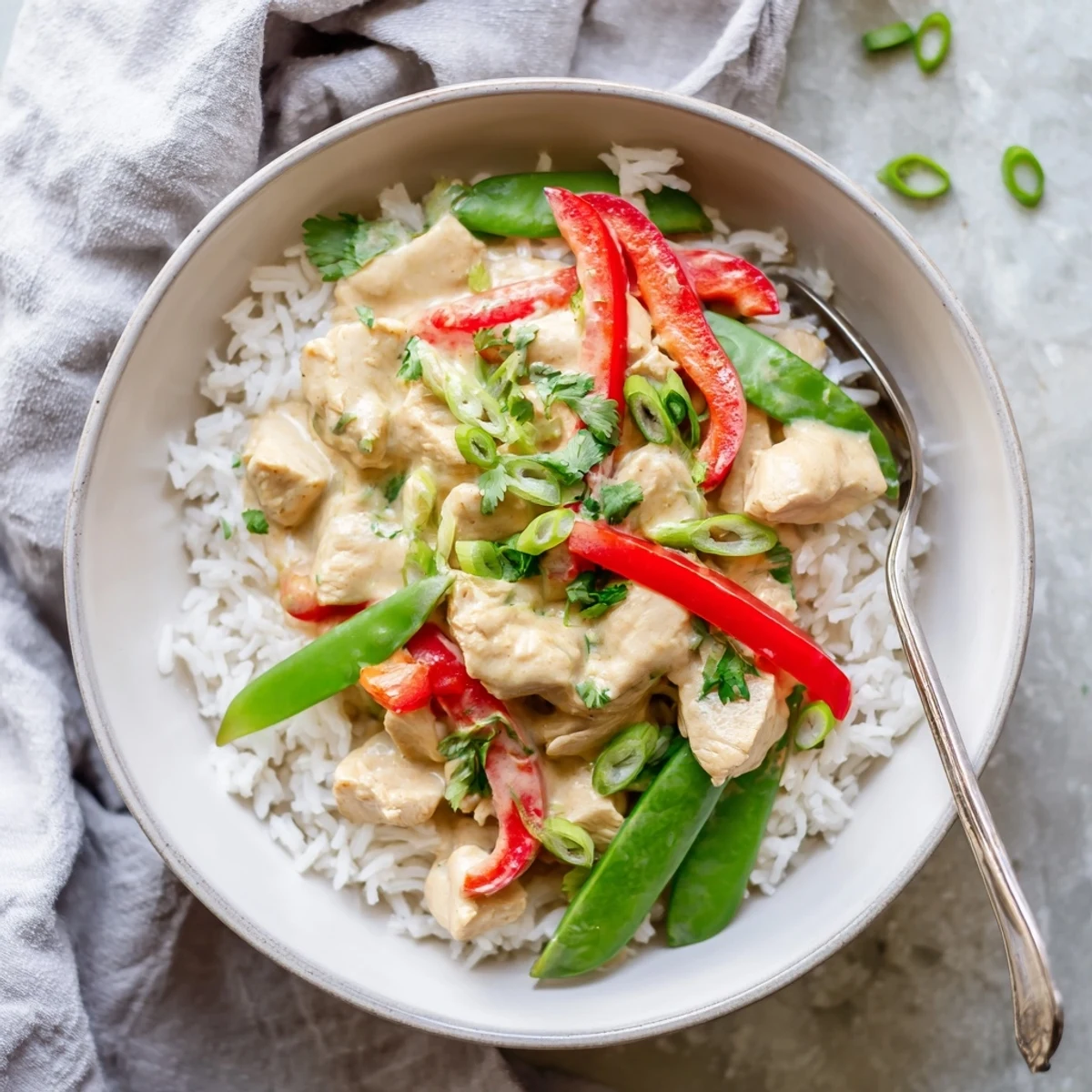 Savory coconut chicken rice bowl garnished with fresh cilantro and colorful bell pepper slices