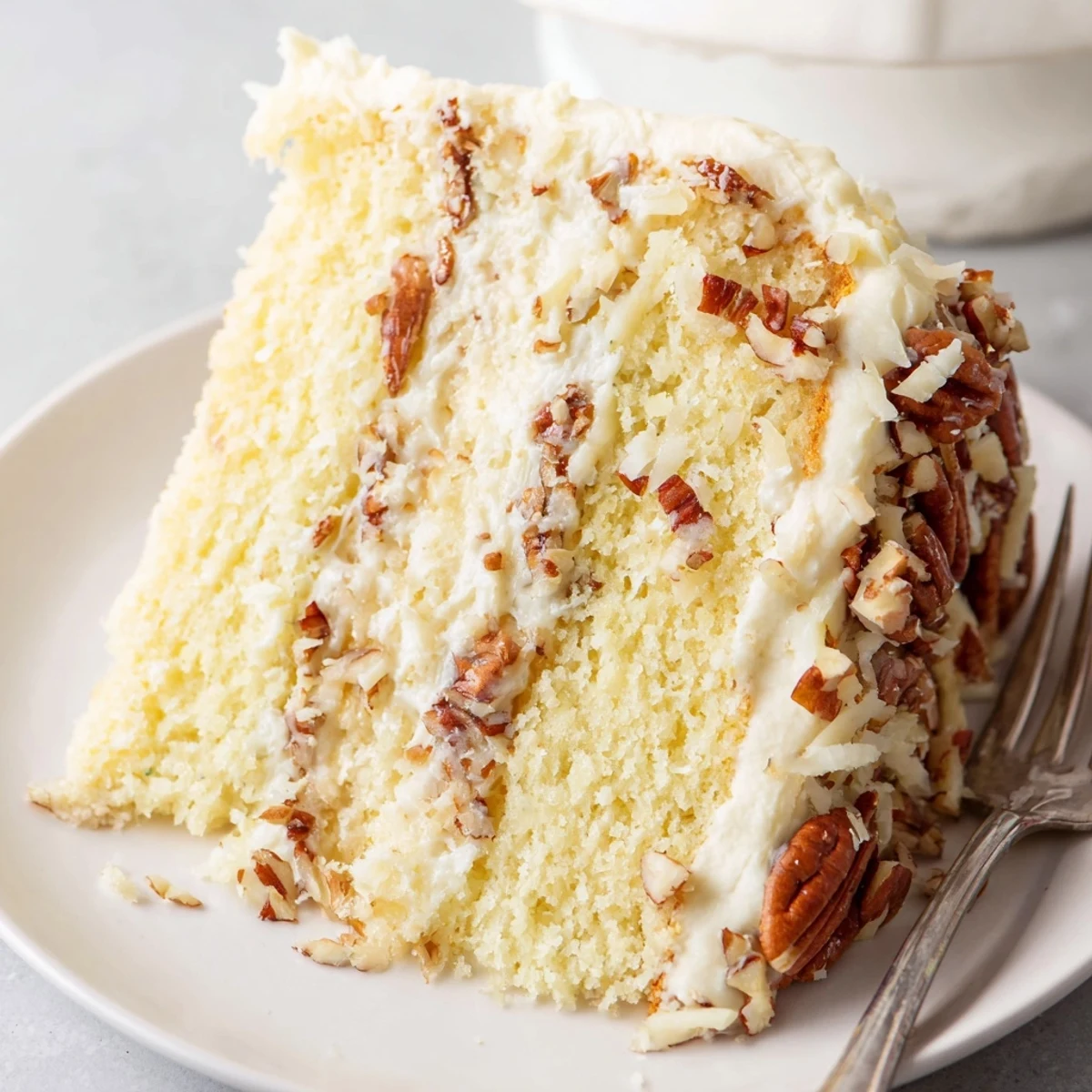 Moist Italian cream cake layers spread with tangy cream cheese frosting and toasted coconut garnish