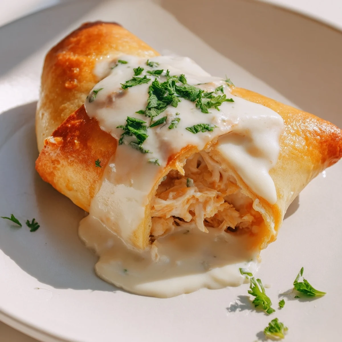 Golden baked chicken pillows with crescent dough drizzled with rich creamy parmesan sauce