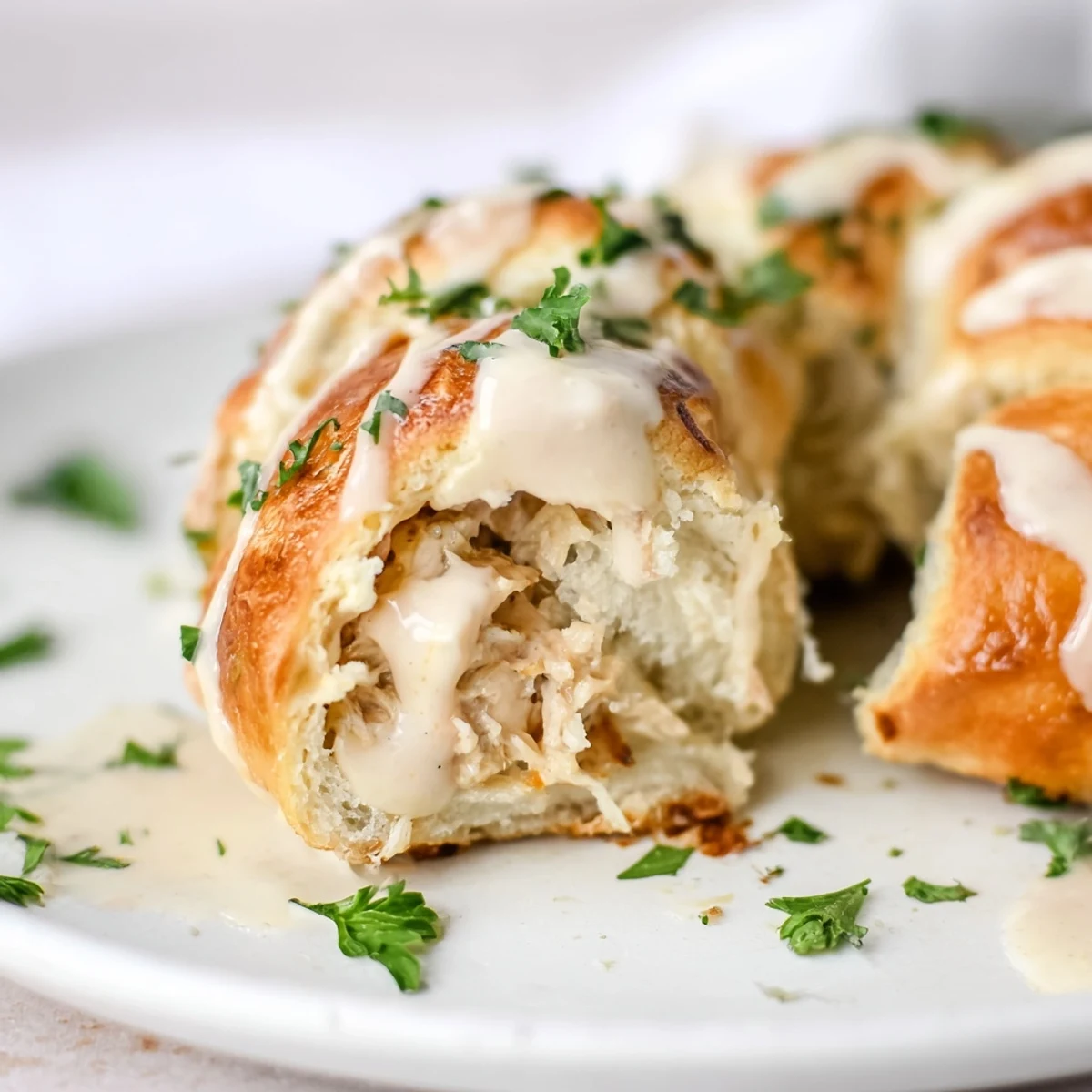 Tender shredded chicken wrapped in flaky pastry topped with white parmesan cream sauce