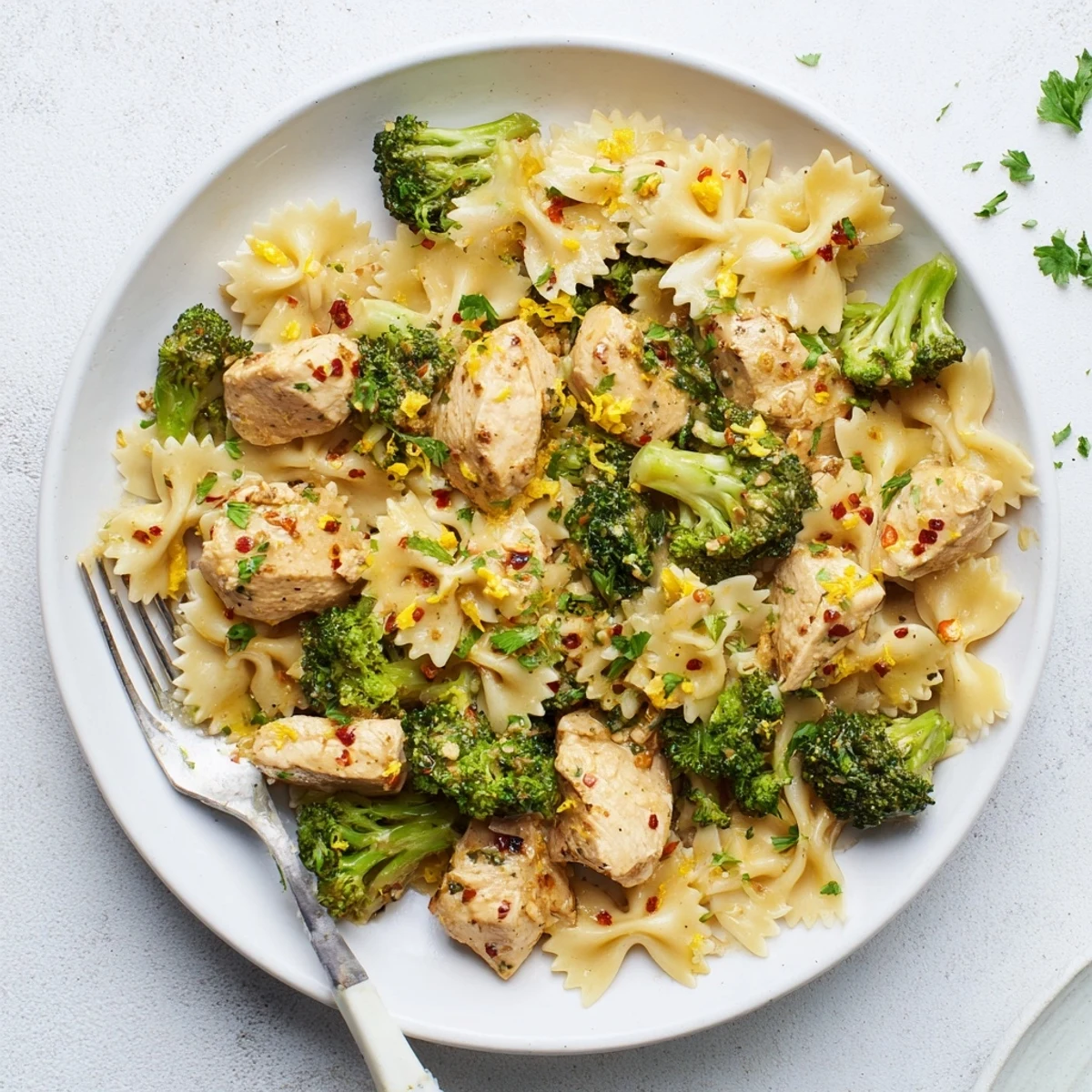 Savory cowboy butter chicken with melted garlic butter sauce plated alongside zesty lemon bowtie pasta and fresh crisp-tender broccoli