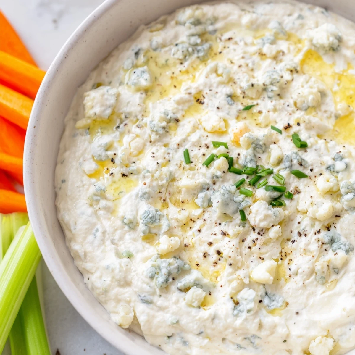 Creamy blue cheese dip flecked with fresh chives, served in a rustic bowl alongside golden potato chips.